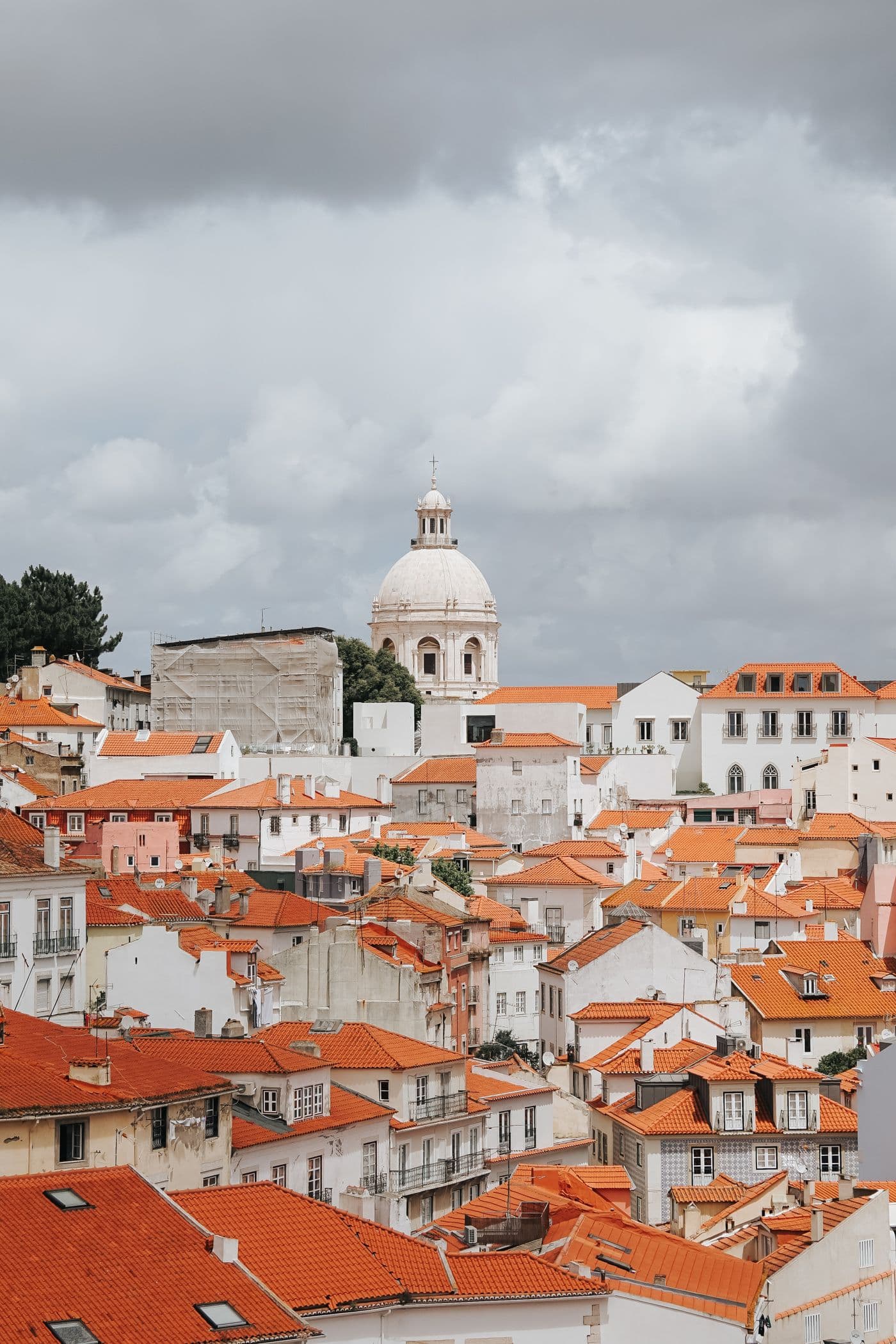 The terracotta rooftops of Lisbon's Alfama district under a heavy sky